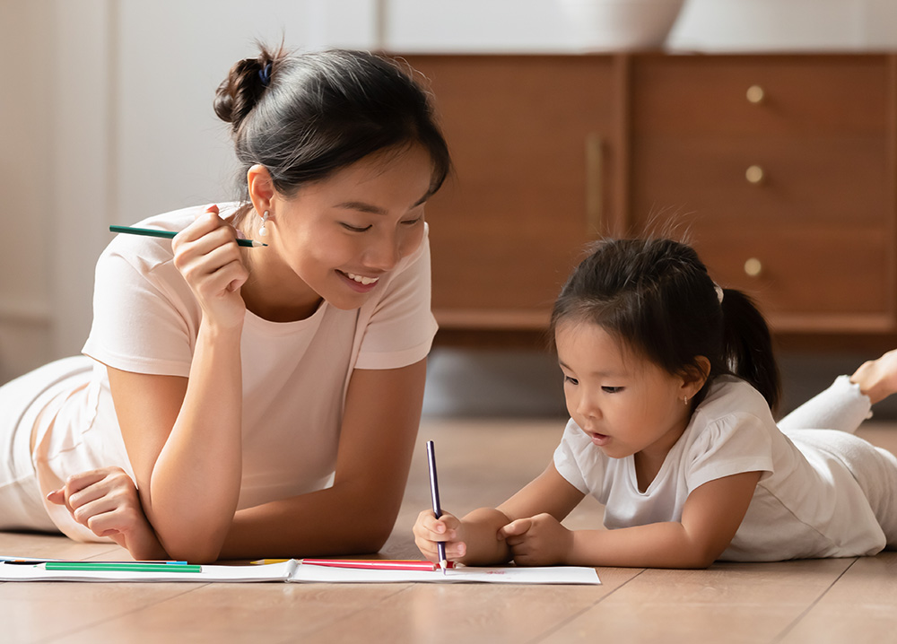 Young Asian Mom and Daughter Coloring on Floor