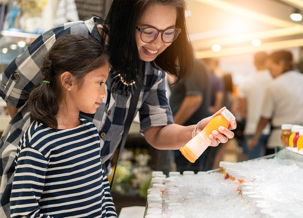 Asian Mother and Daughter Buying Orange Juice