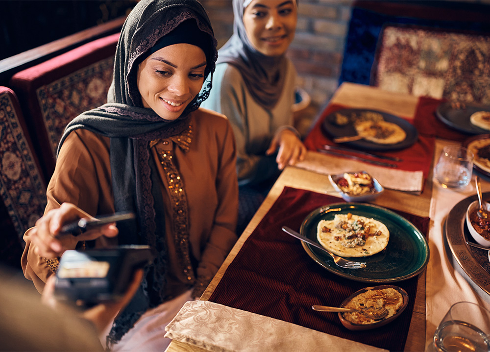 Muslim Woman Paying for Dinner at Restaurant