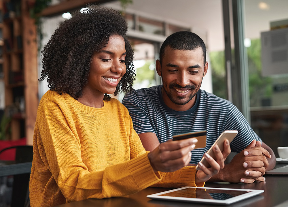 Couple Smiling and Holding Credit Card and Mobile Phone