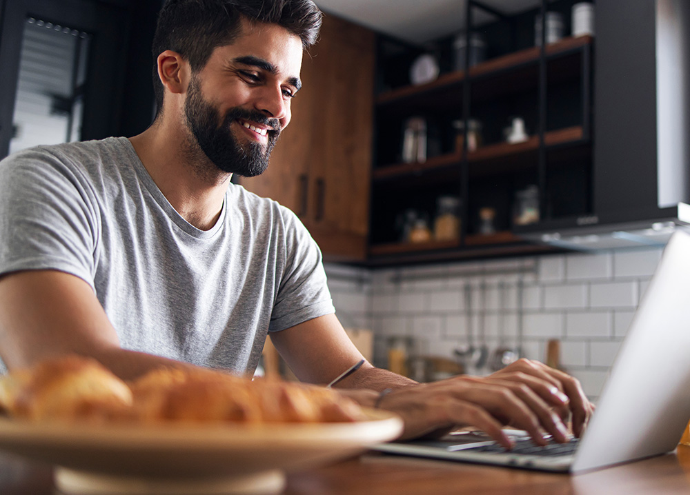 Young Man Using Laptop in Kitchen