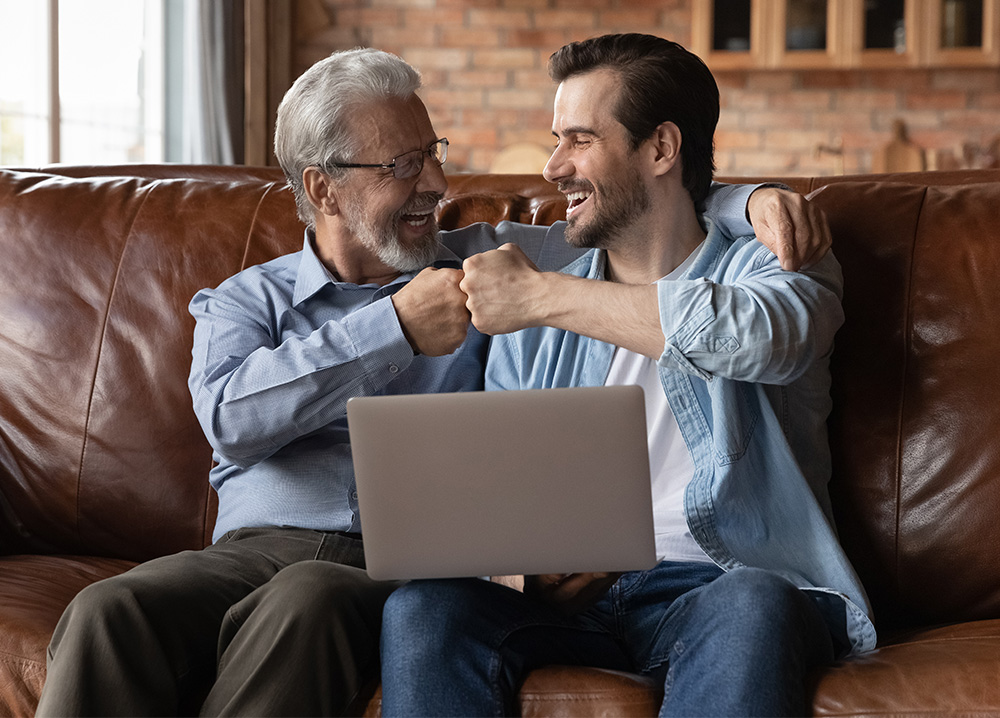 Father and Adult Son Fist Bumping on Couch