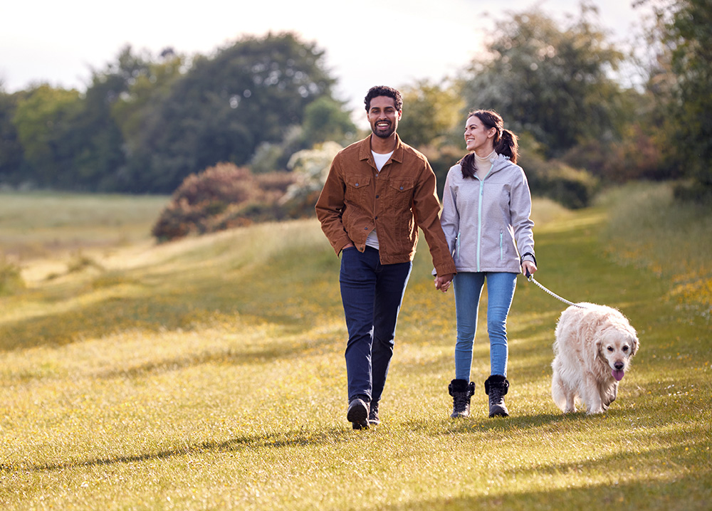 Couple Walking with Dog in Field